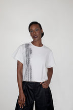 Person wearing a white t-shirt with a black and white pattern on a plain background