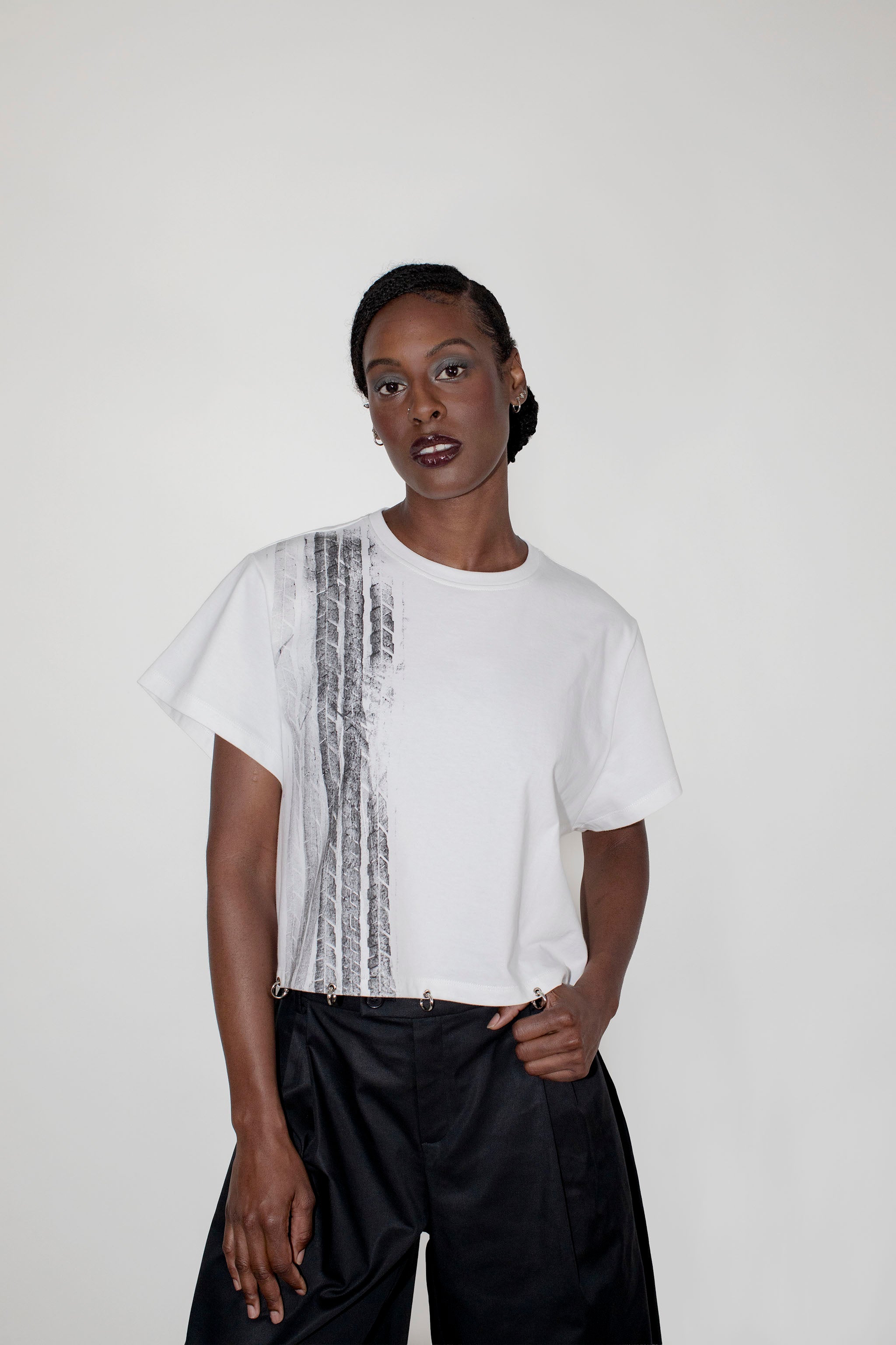 Person wearing a white t-shirt with a black and white pattern on a plain background