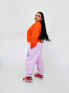 Person wearing an orange sweatshirt and blush sweatpants on a white background