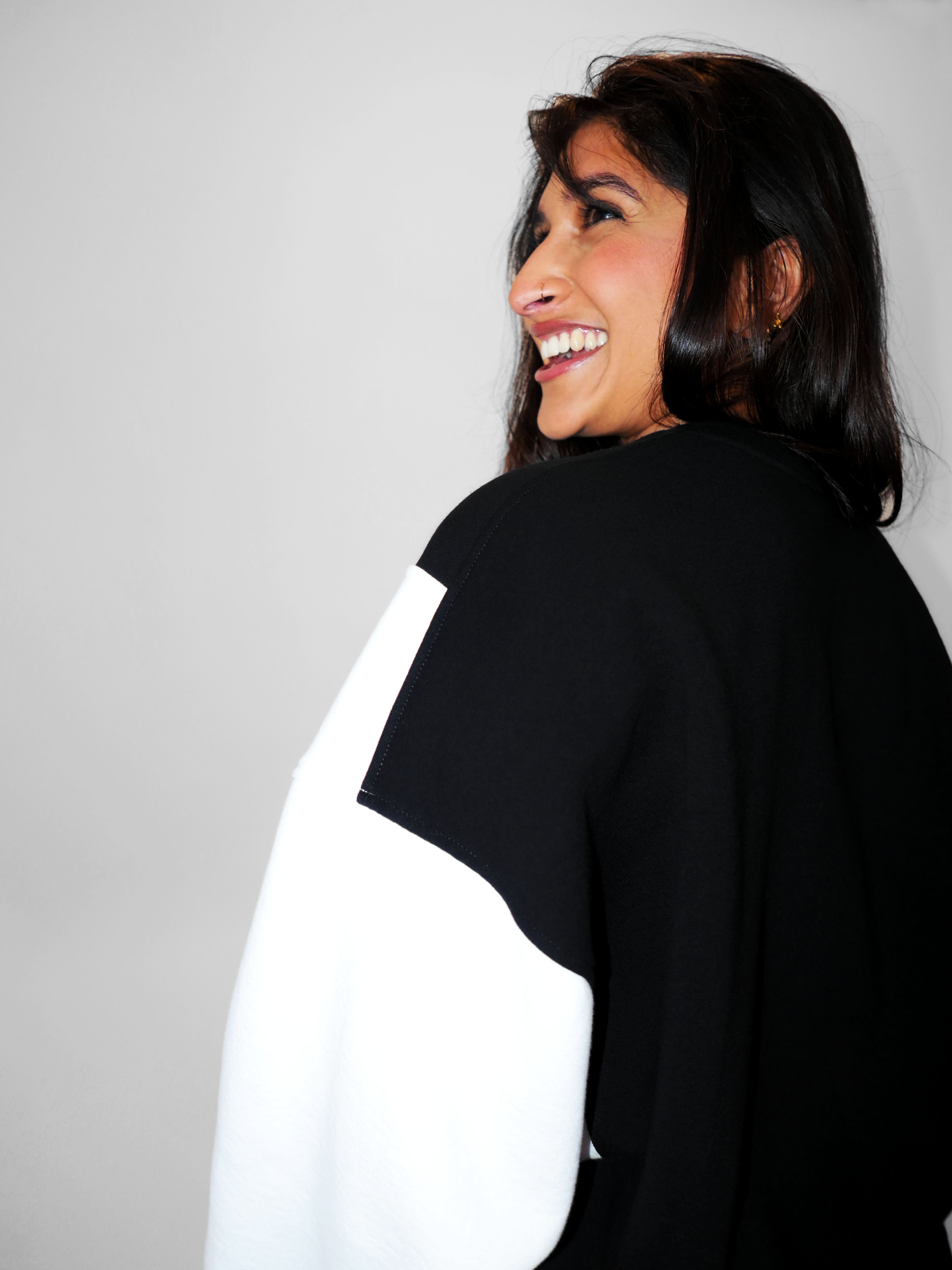 Woman wearing a black and white oversized crewneck against a gray background