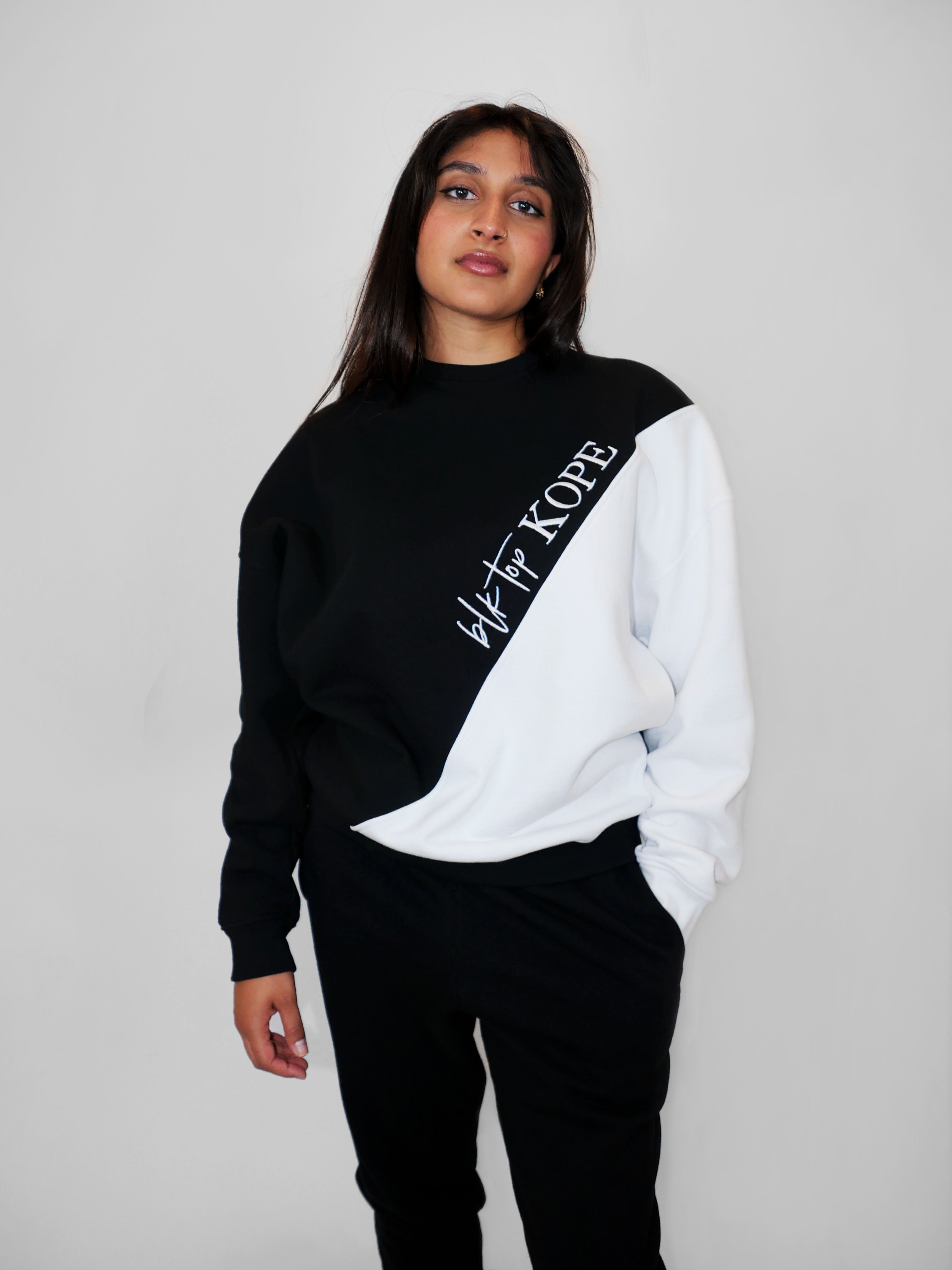 Woman wearing a black and white oversized crewneck with text on a plain background