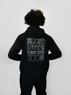 Person wearing a black hoodie with text on the back against a white background