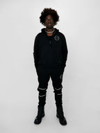 Person wearing a black outfit with white accents on a white background