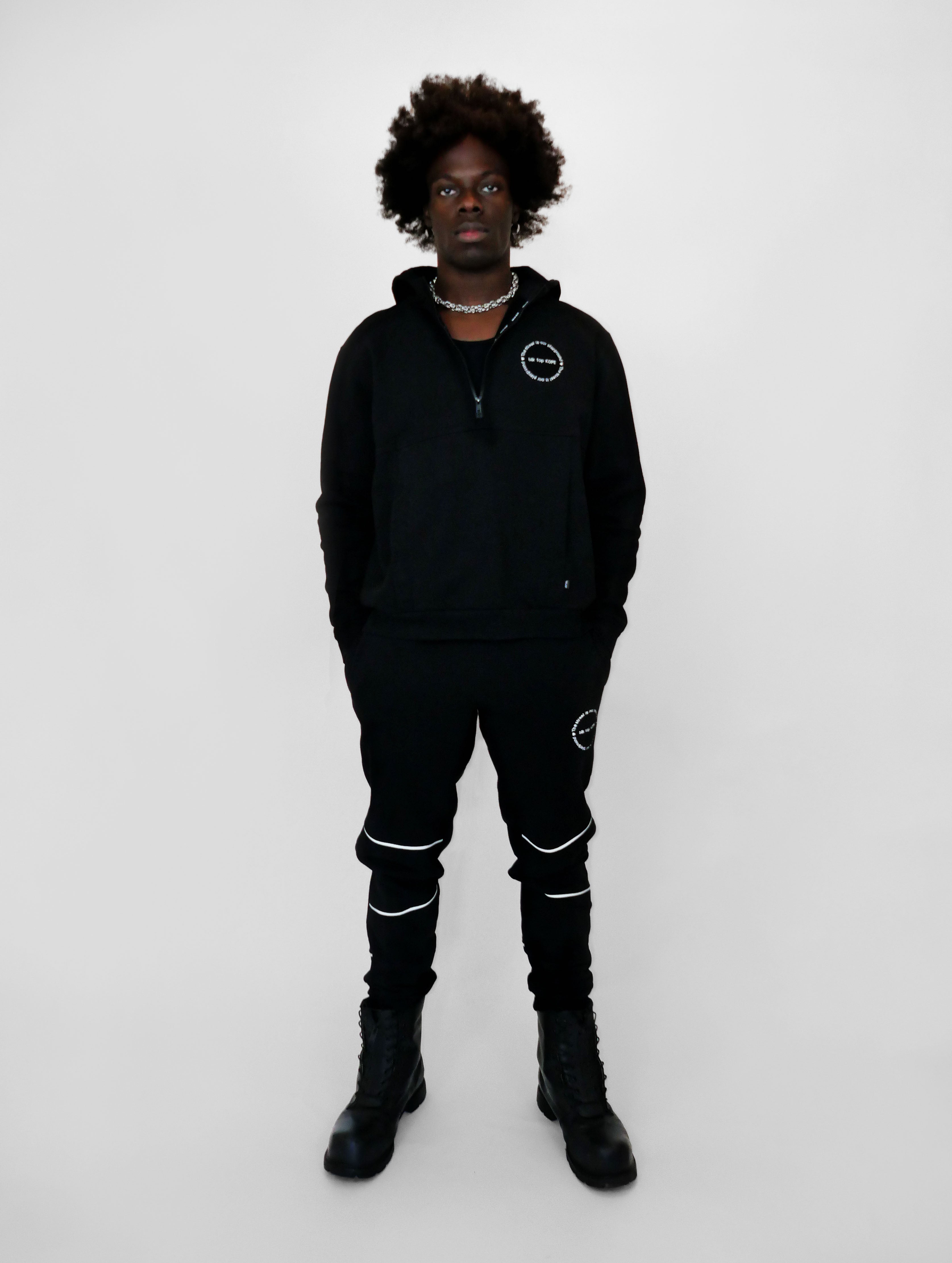 Person wearing a black outfit with white accents on a white background