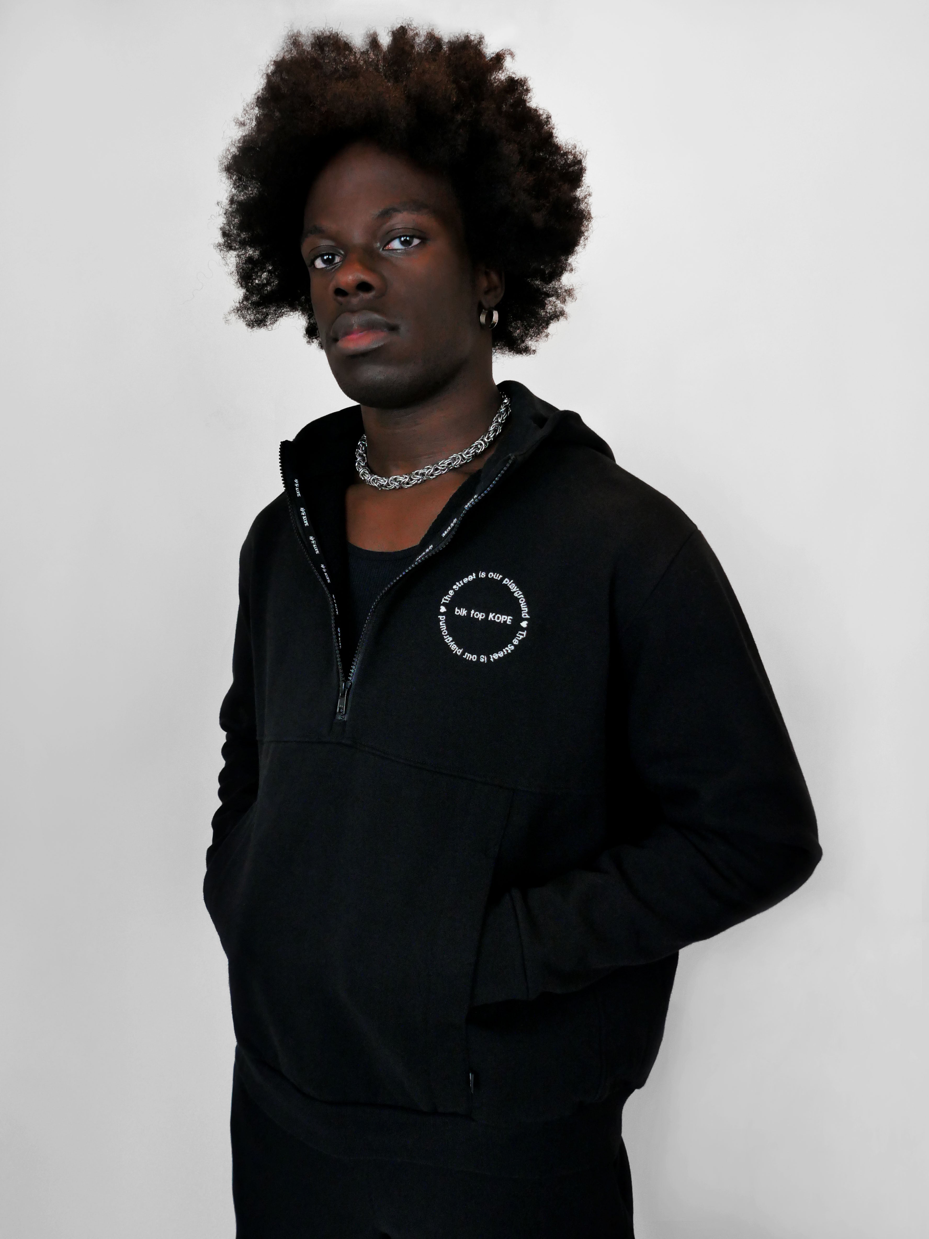 Person wearing a black zip-up hoodie with a logo on a white background