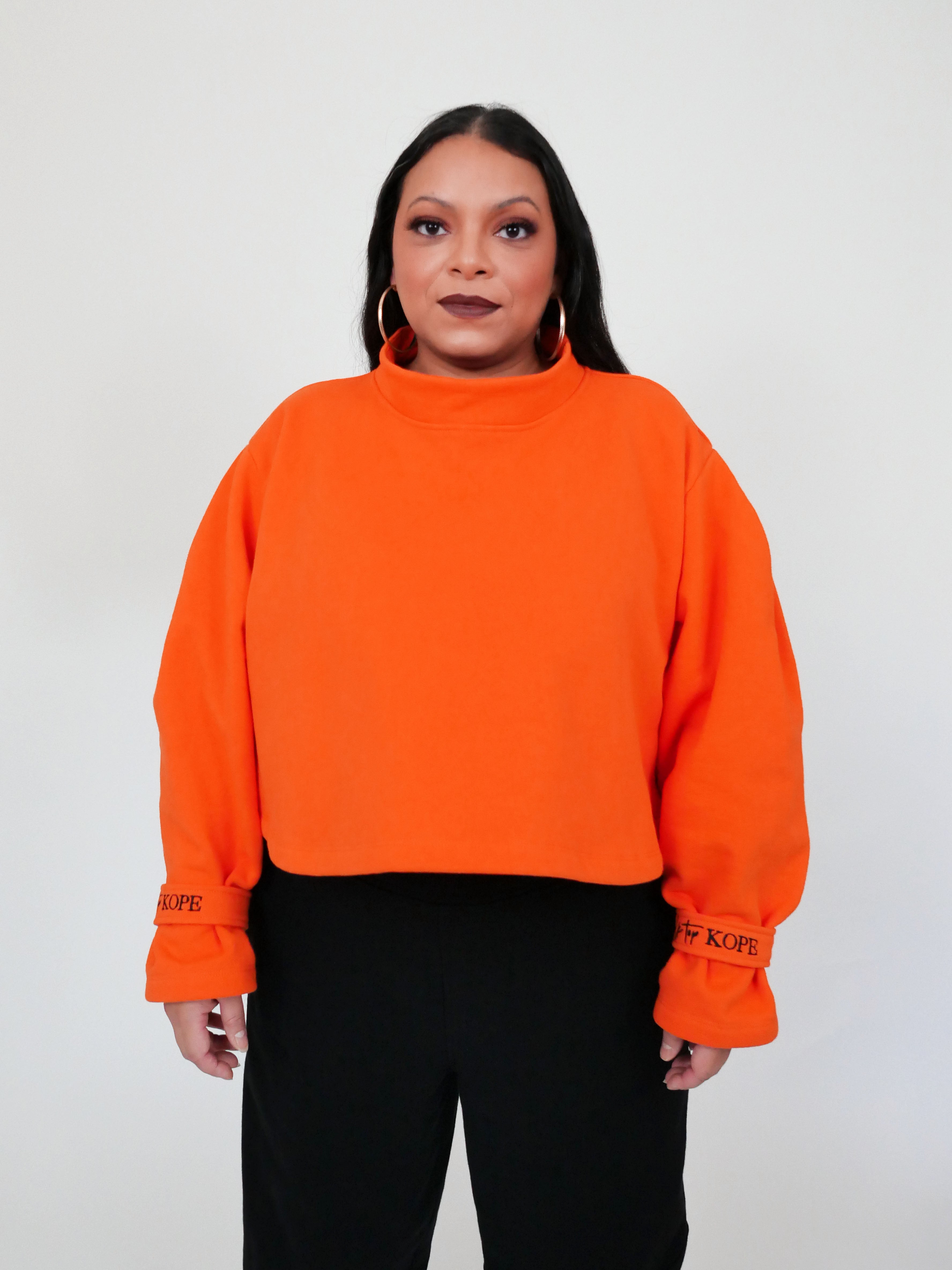 Person wearing an orange sweatshirt with text on sleeves against a white background