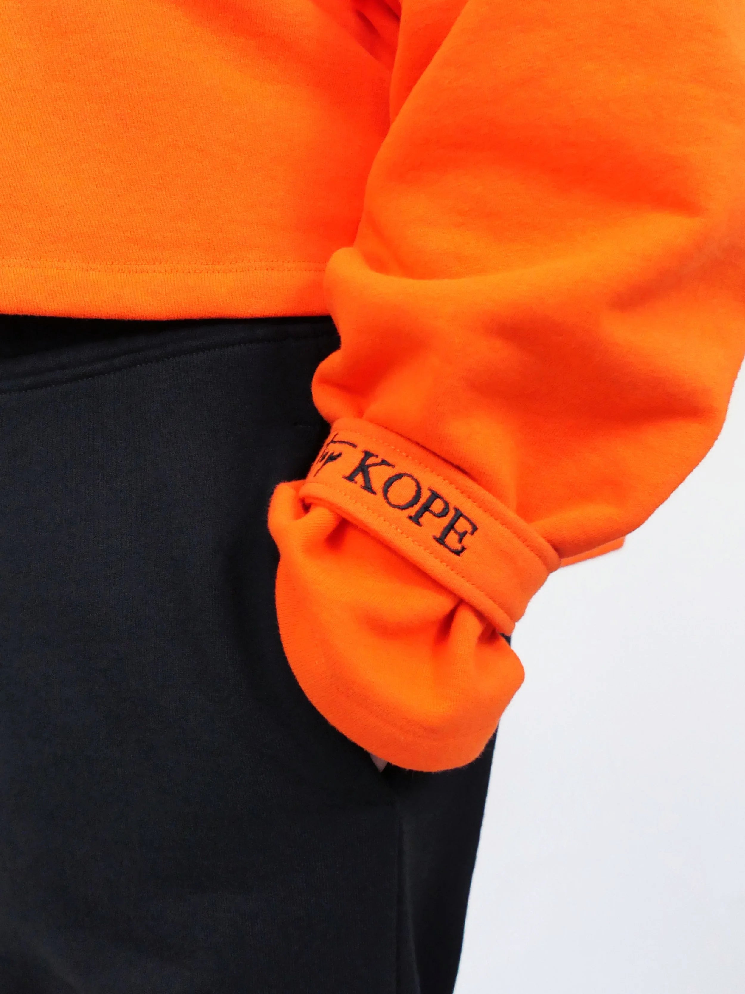 Close-up of an orange sweatshirt with 'blk top Kope' branding on a white background