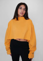 Person wearing a yellow sweater with black sweatpants on a plain background