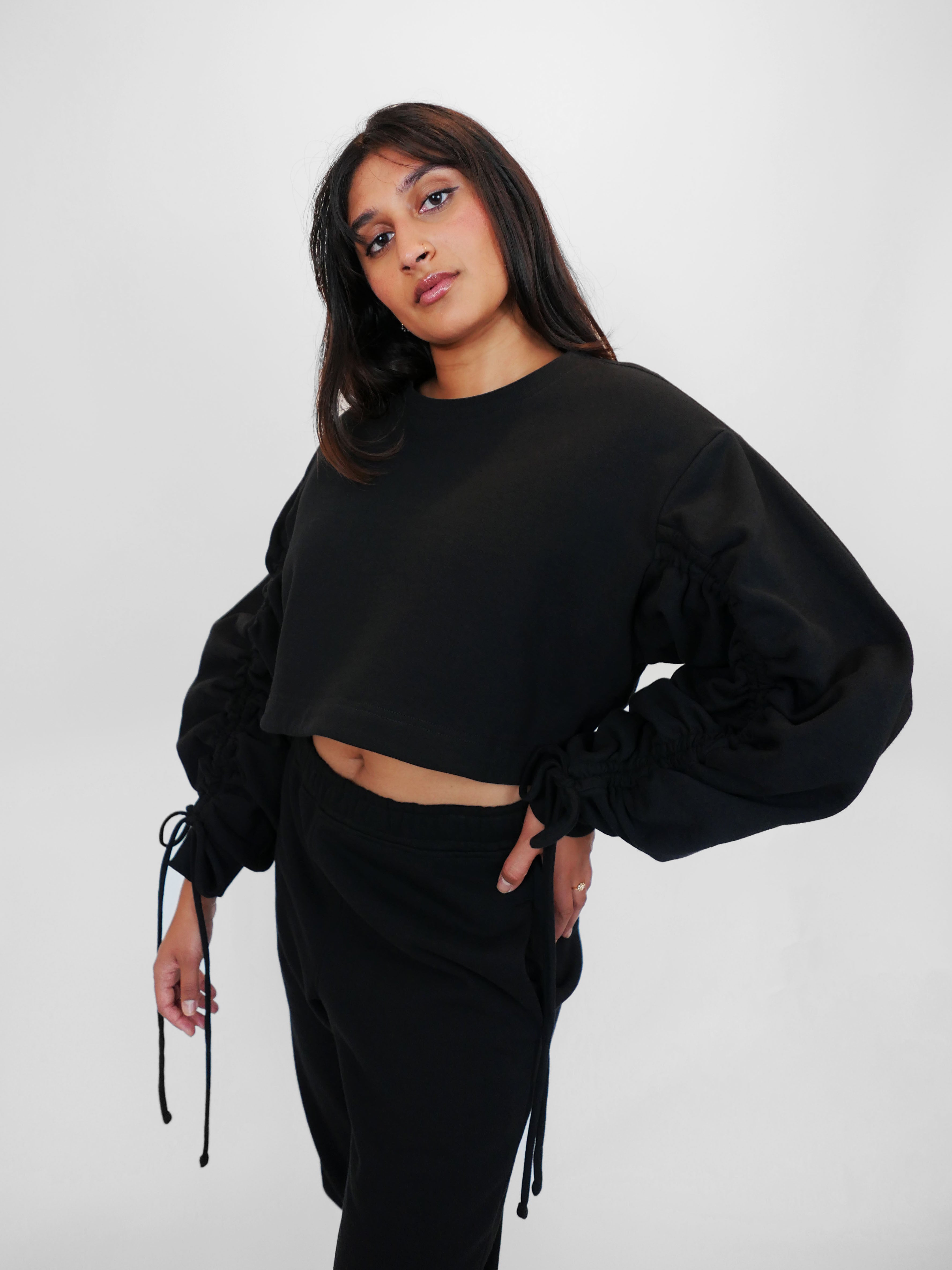 Woman wearing a black outfit with puffed sleeves on a white background