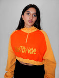 Person wearing a yellow and orange half zip-up with a logo design on a gray background