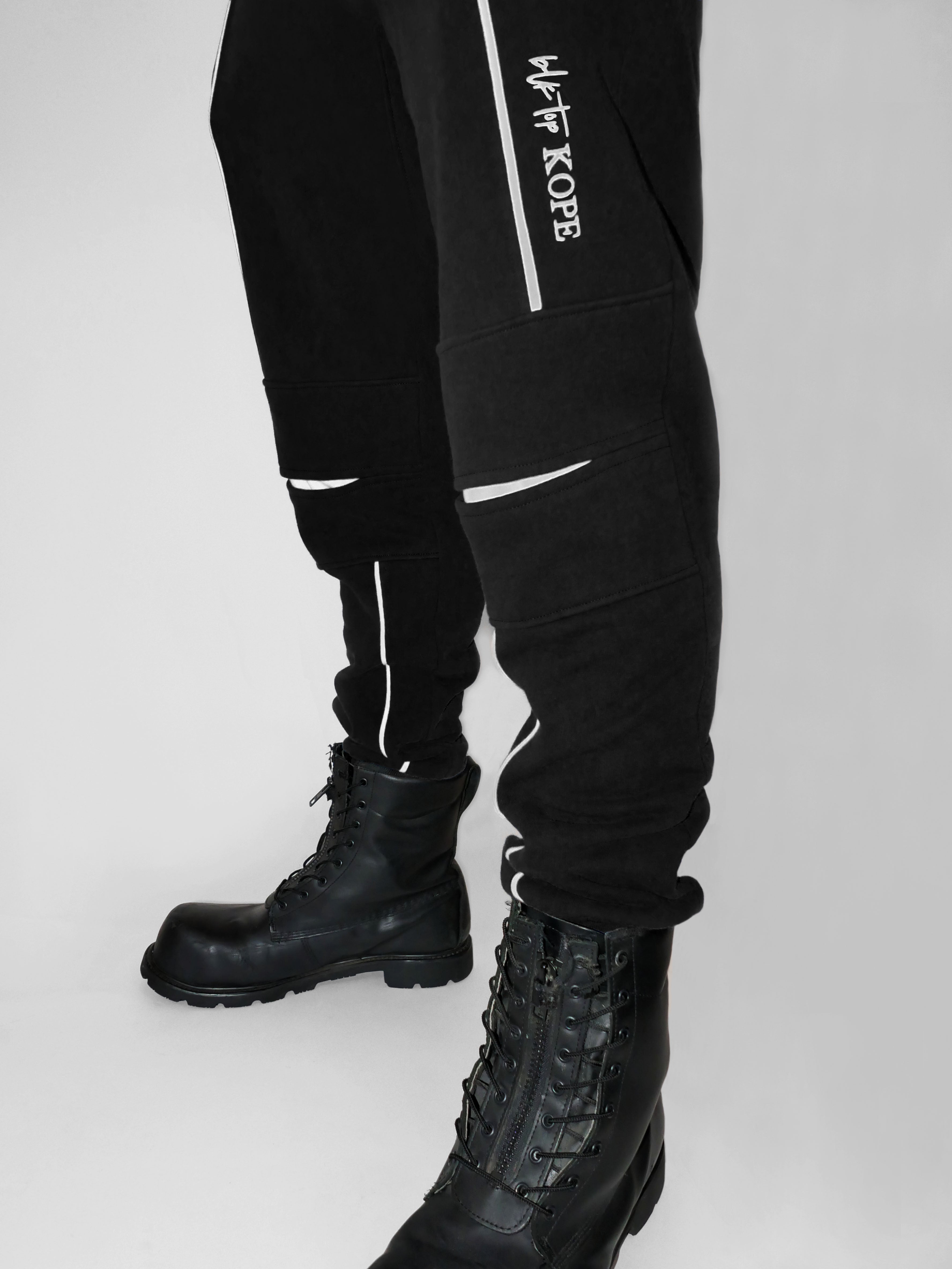 Black sweatpants with a brand logo and black boots on a white background