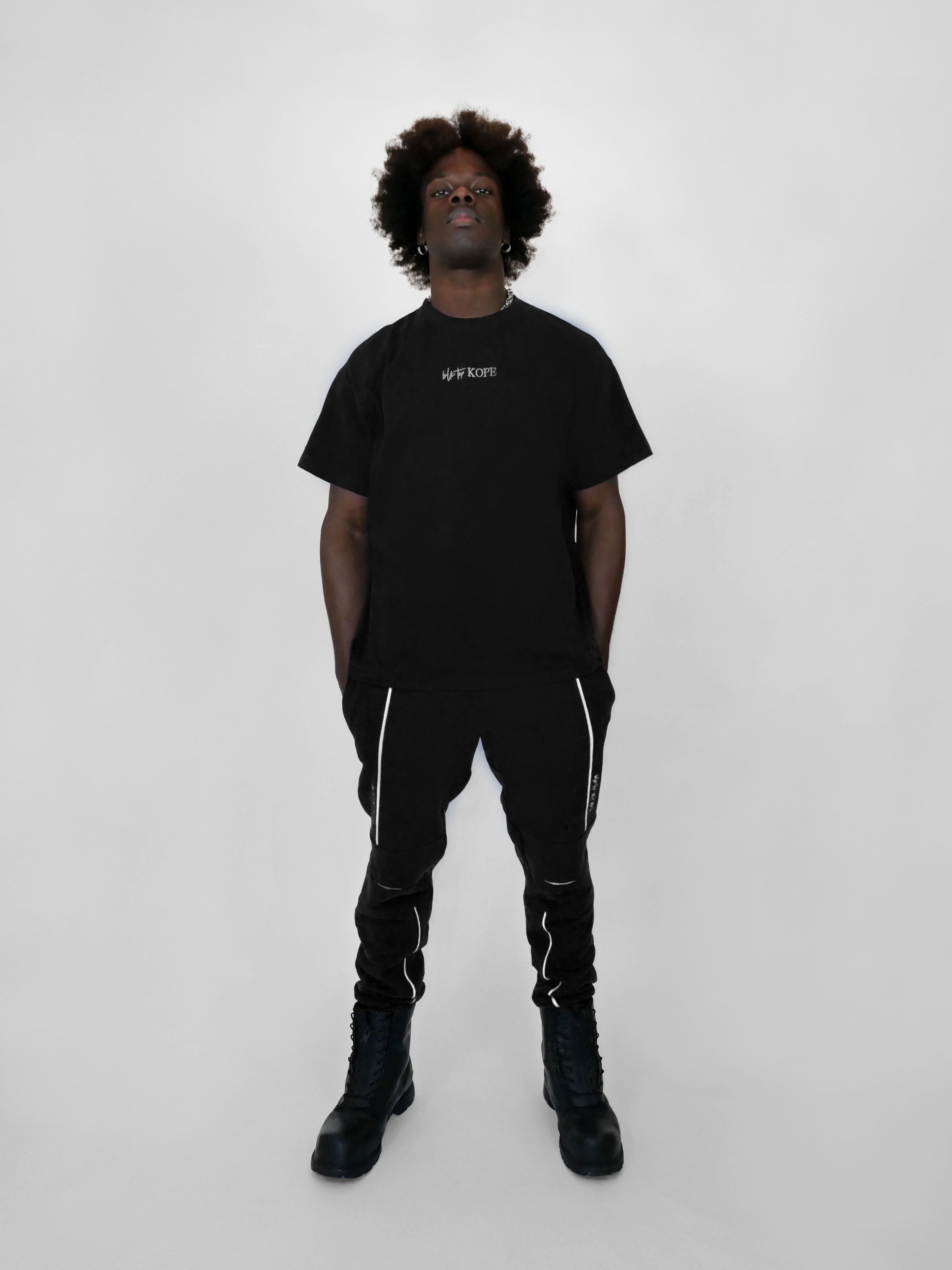 Person wearing a black t-shirt and sweatpants with white text on a white background