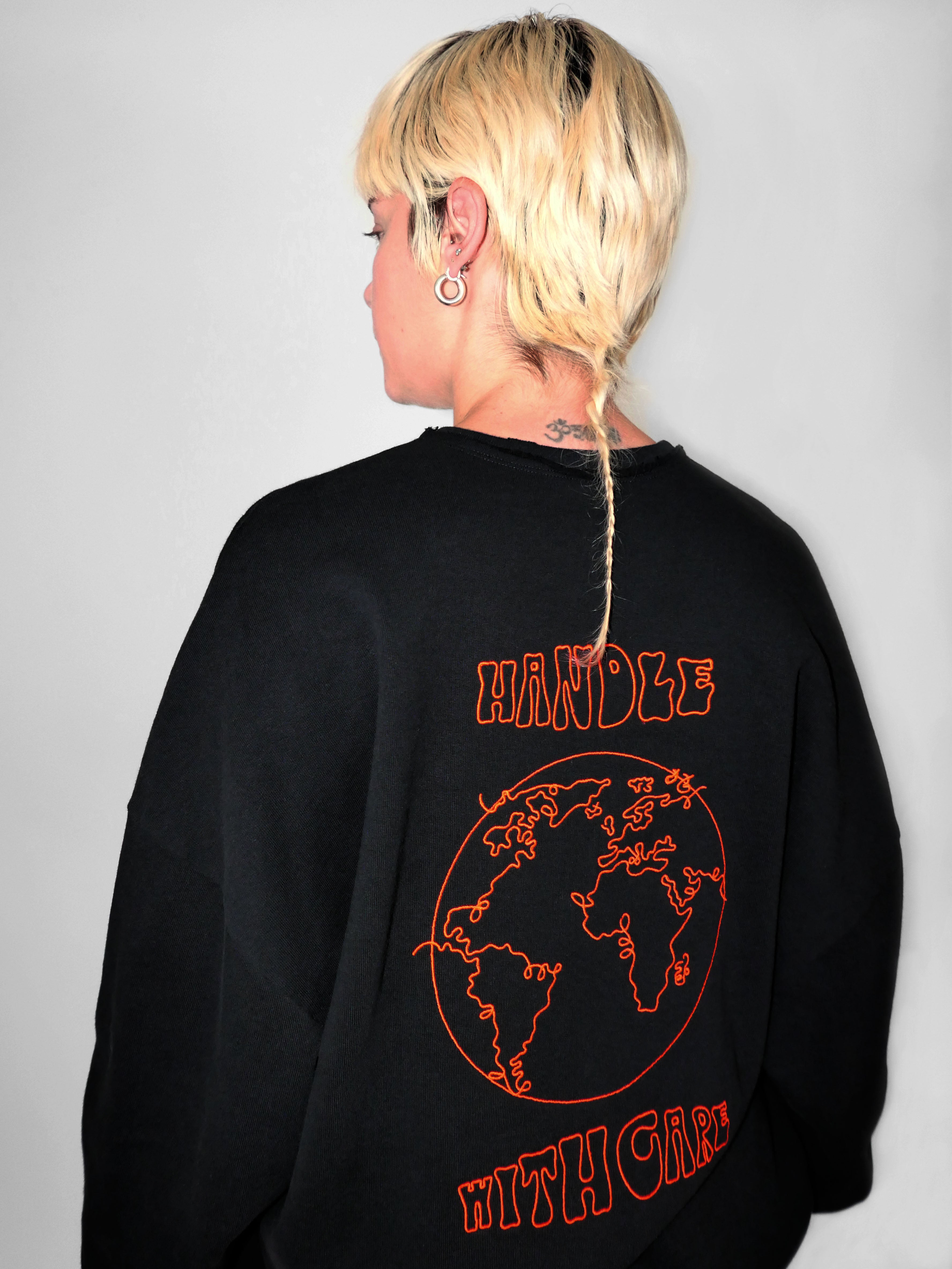 Woman wearing a black sweatshirt with red text and graphics on the back against a gray background