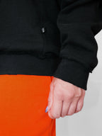 Closeup of hem of a black crewneck with a neutral background