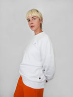 Person wearing a white sweatshirt and orange pants against a plain background