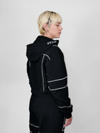 Person wearing a black full zip hoodie with white piping on a plain background