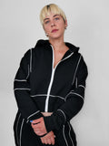 Person wearing a black full zip hoodie with white piping against a plain background