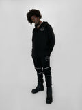 Person wearing a black outfit with white accents on a white background