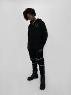 Person wearing a black outfit with white accents on a white background