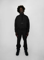 Person wearing a black tracksuit with a brand logo on a white background