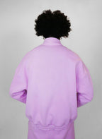 Person wearing a blush tracksuit with a plain background