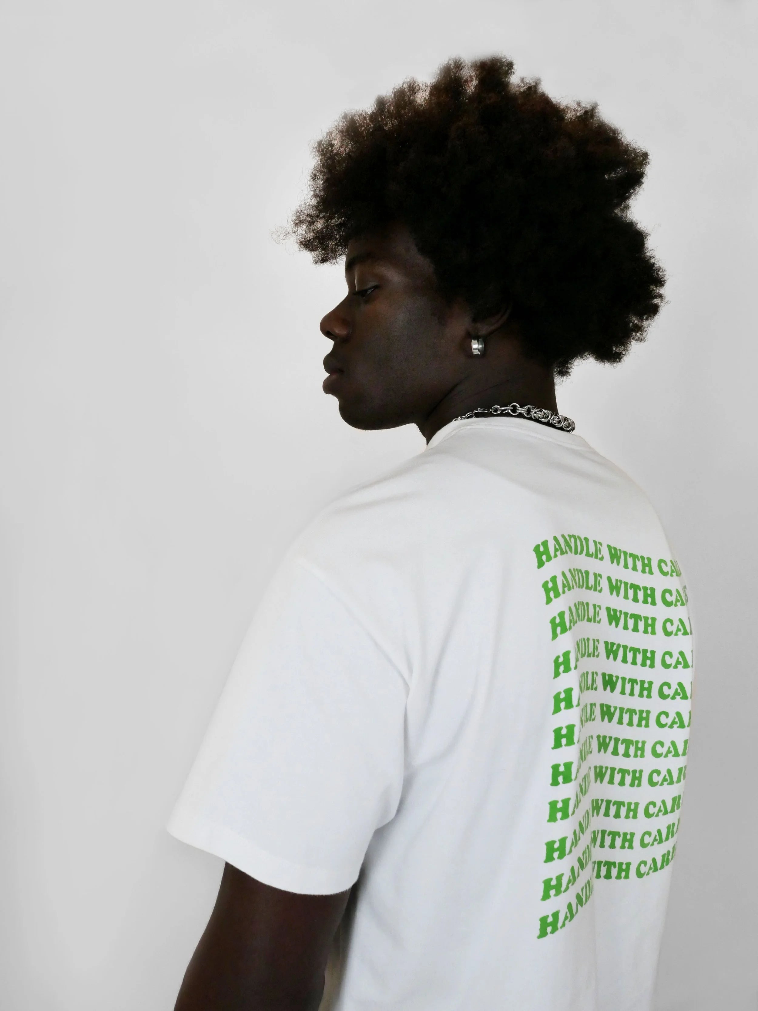 Person wearing a white t-shirt with green text on the back against a plain background