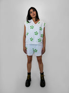 Person wearing a white sleeveless top and shorts with green floral pattern on a plain background