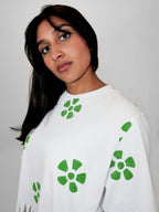Person wearing a white t-shirt with green floral patterns on a plain background