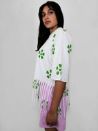 Woman wearing a white t-shirt garment with green floral patterns and blush shorts on a plain background