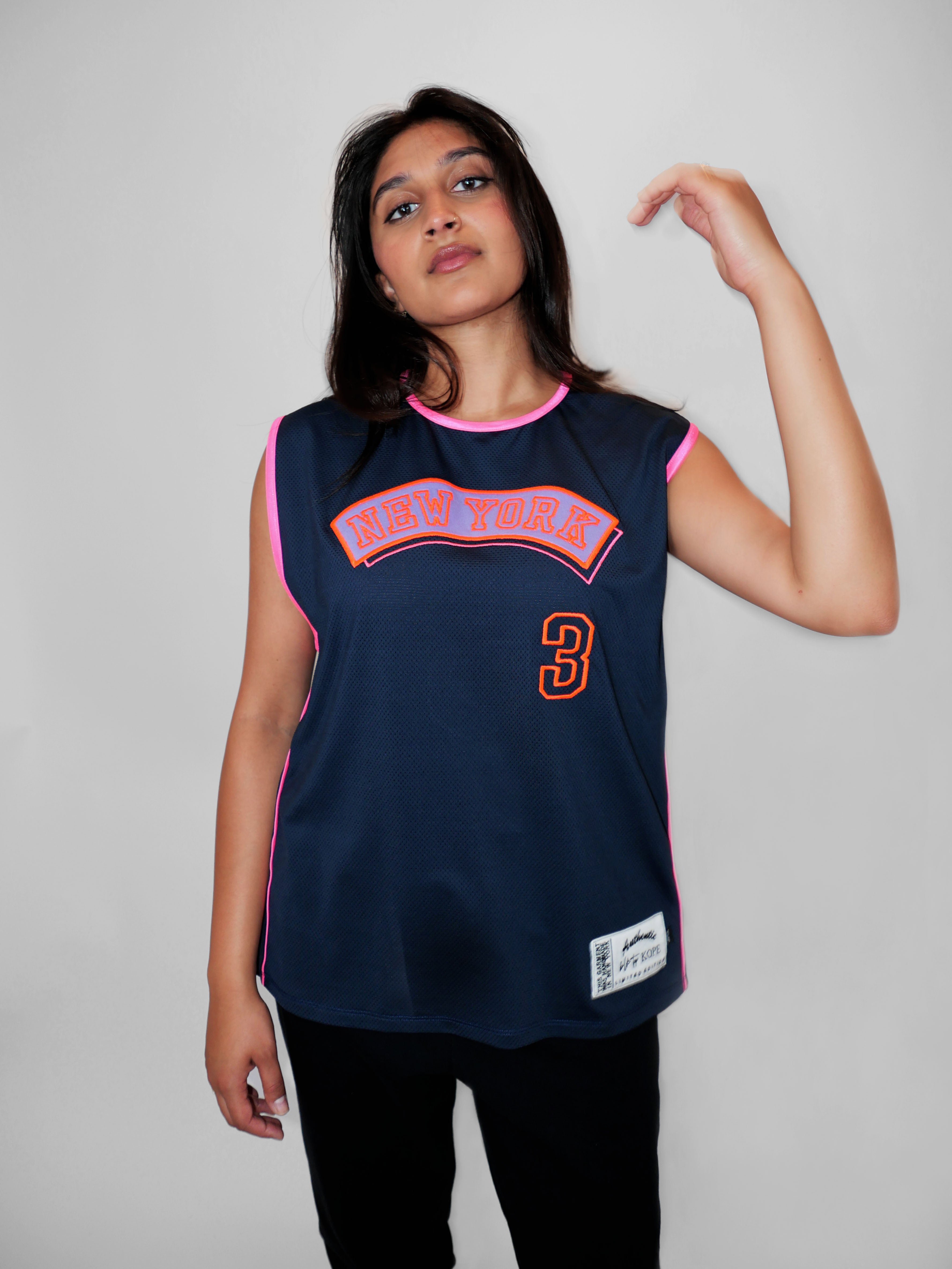 Person wearing a navy blue sports jersey with pink and orange details on a plain background