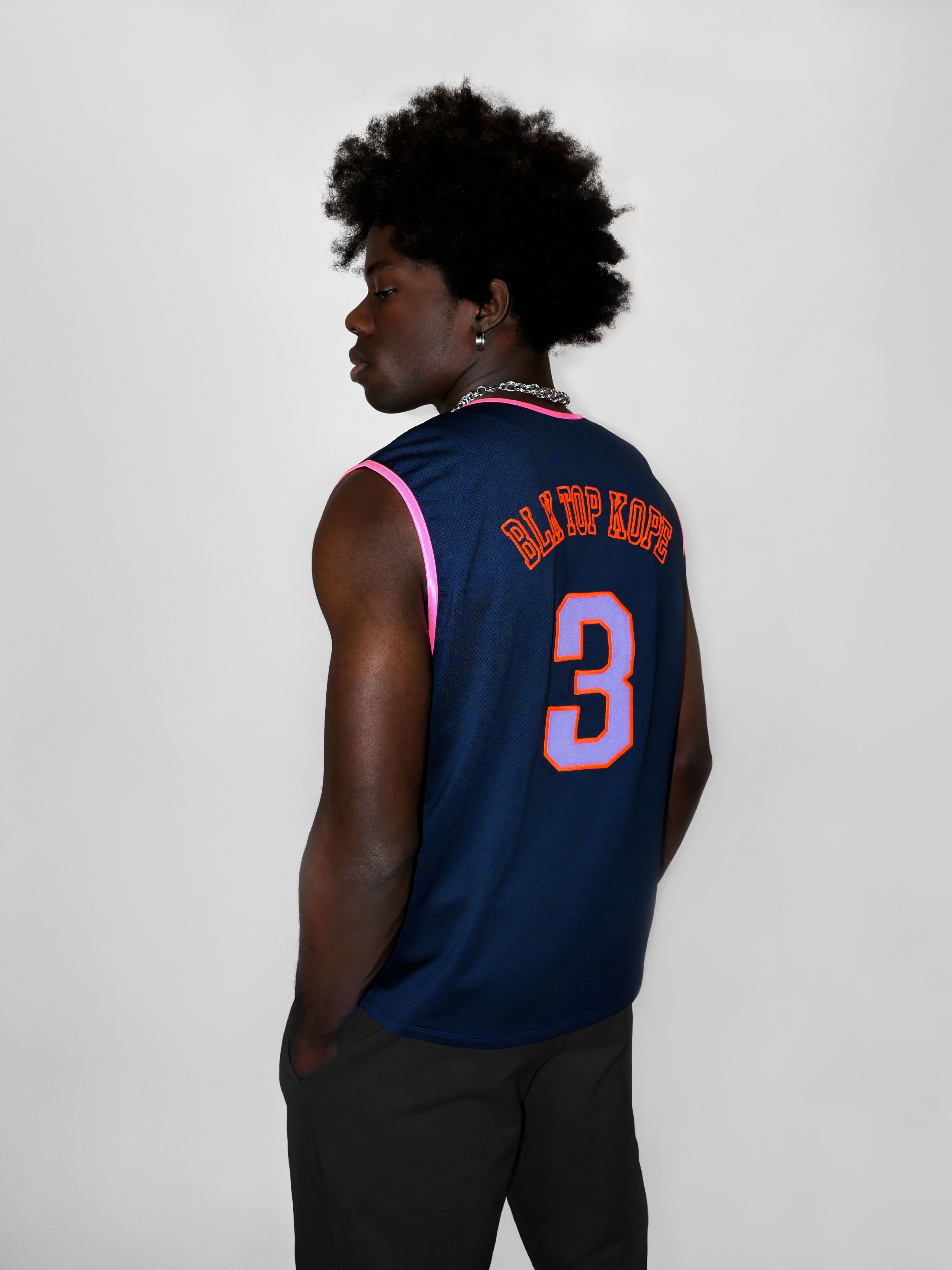 Man wearing a navy blue basketball jersey with pink and orange text on a white background