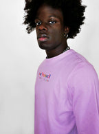Person wearing a blush t-shirt with colorful text on a plain background