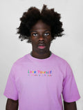 Person wearing a blush t-shirt with 'Love Yourself' text on a plain background