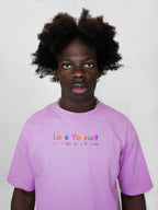Person wearing a blush t-shirt with 'Love Yourself' text on a plain background