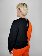 Person wearing a black and orange outfit against a plain background