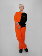 Person wearing a black and orange outfit with text on a plain background