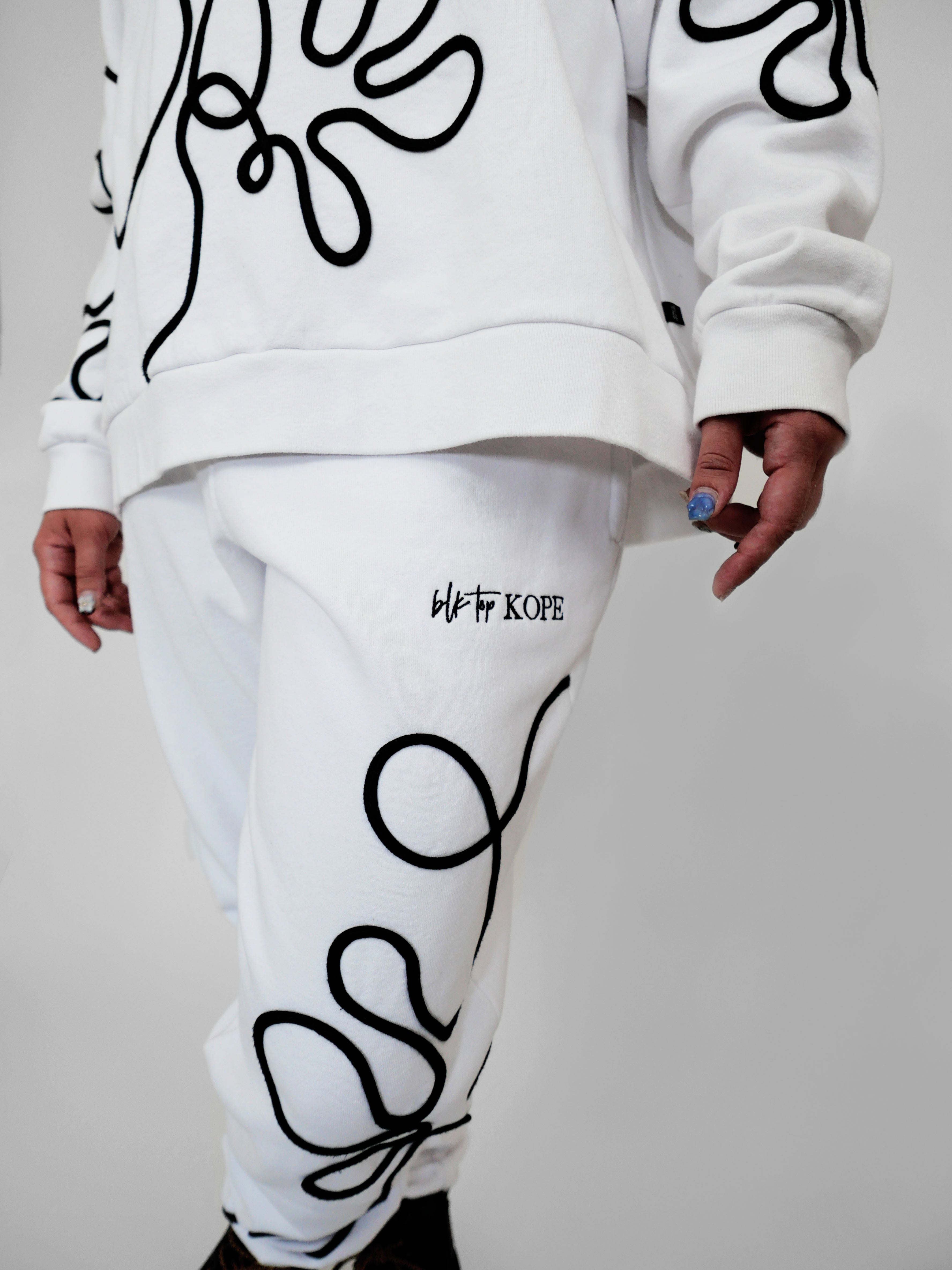 White sweatpants with black abstract one-line designs on a plain background