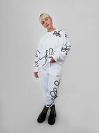 Person wearing a white outfit with black abstract one-line designs on a plain background