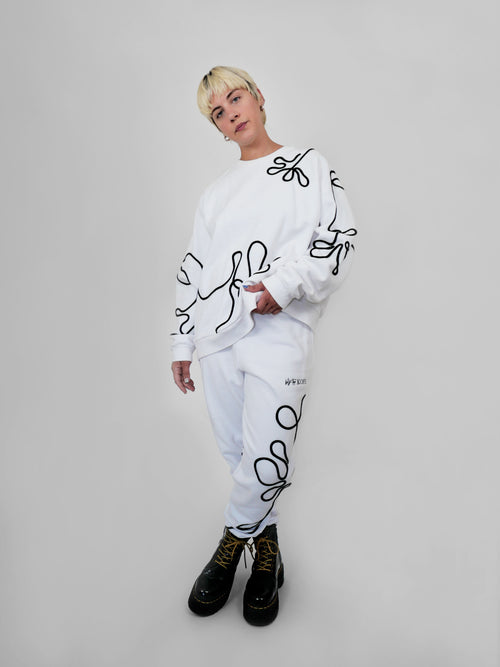 Person wearing a white outfit with black abstract one-line designs on a plain background
