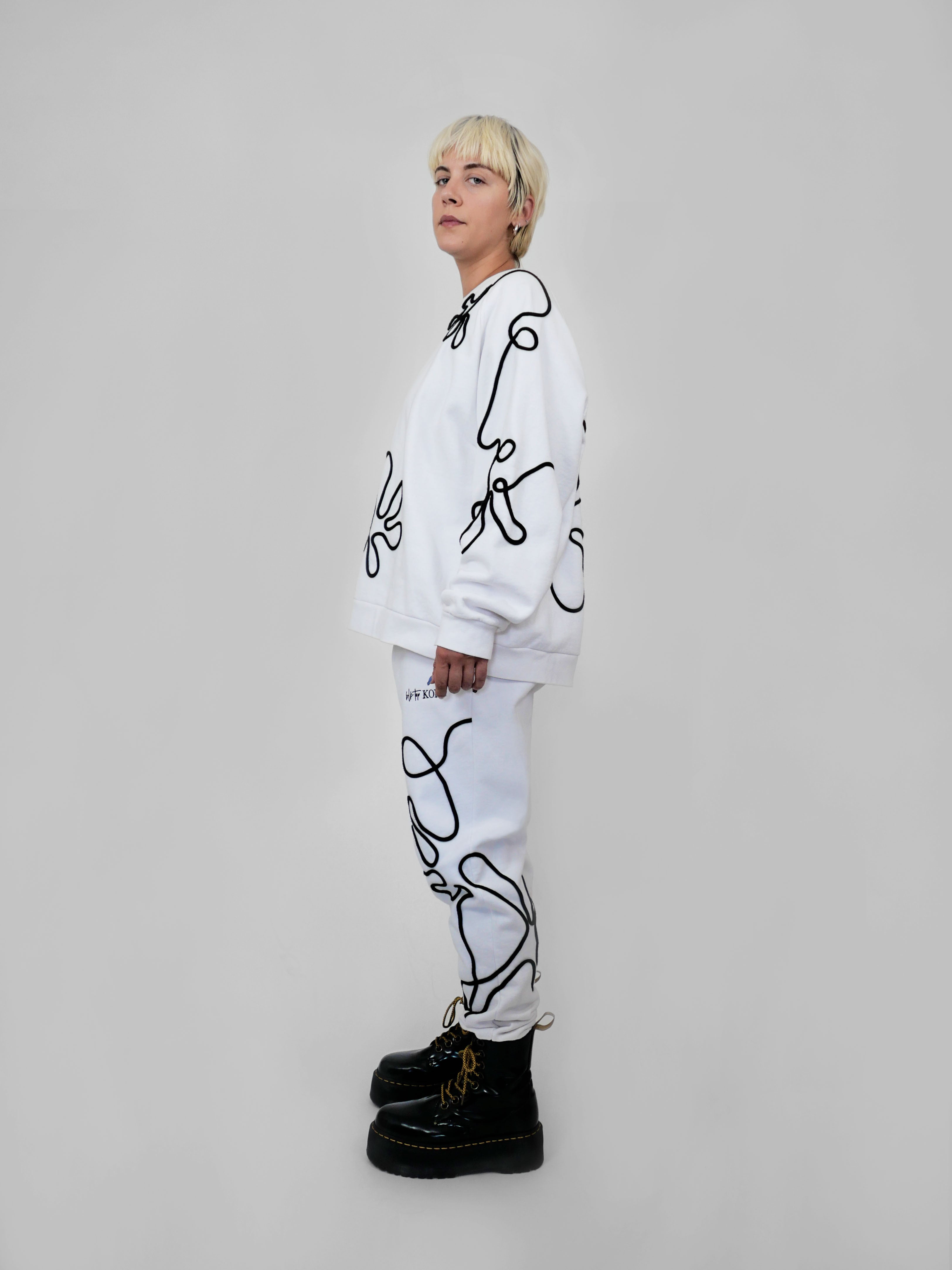 Person wearing a white outfit with black abstract one-line designs on a plain background