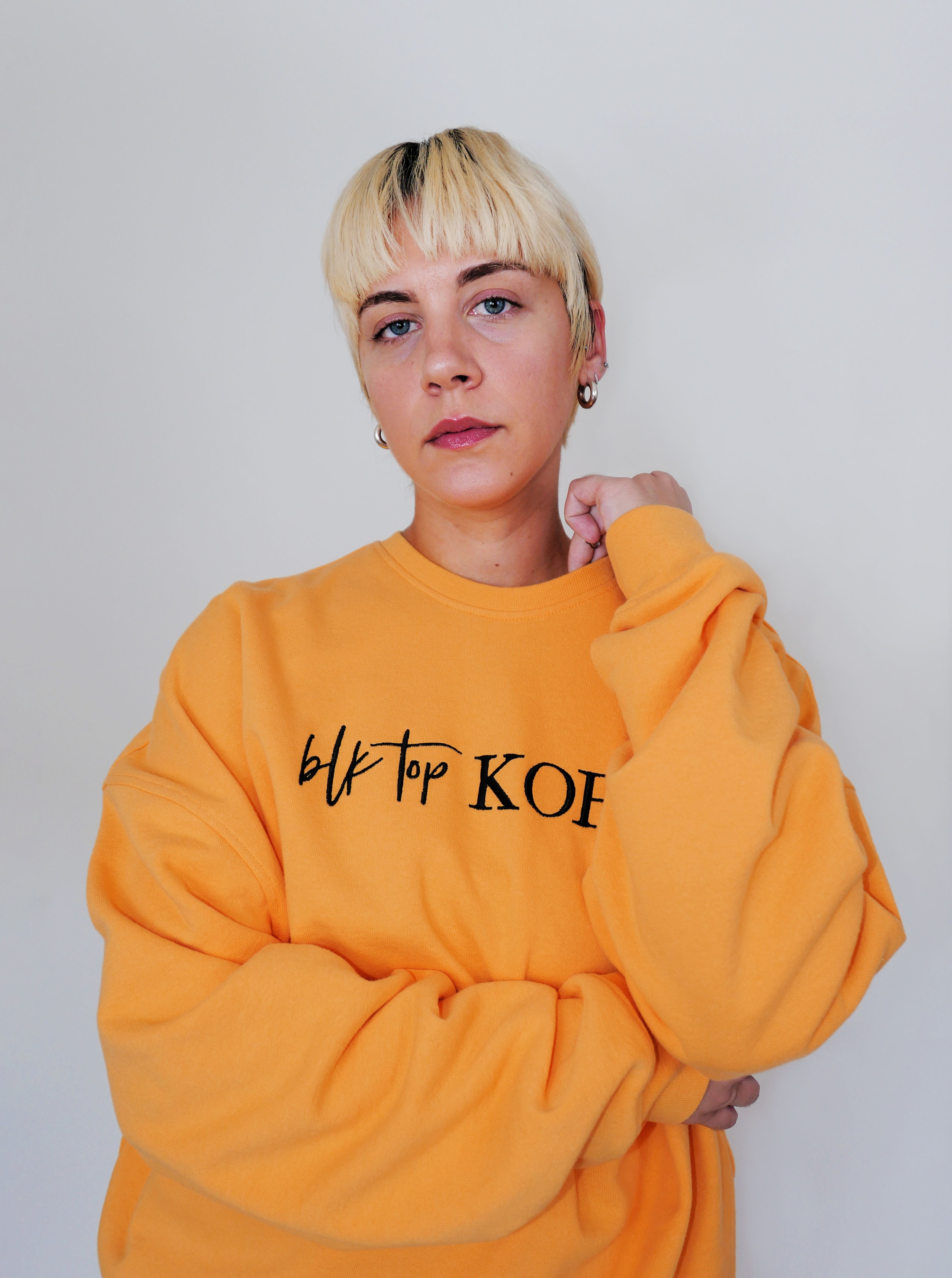 Person wearing a yellow crewneck with black text on a plain background