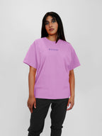 Person wearing a blush t-shirt with a brand logo on a white background