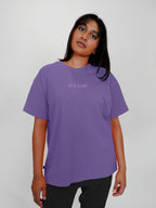 Person wearing a lavender t-shirt with text on a plain background