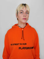 Person wearing an orange hoodie with text on a plain background