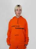 Person wearing an orange hoodie with text on a plain background