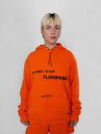 Person wearing an orange hoodie with text on a plain background
