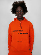Person wearing an orange hoodie with text on a plain background