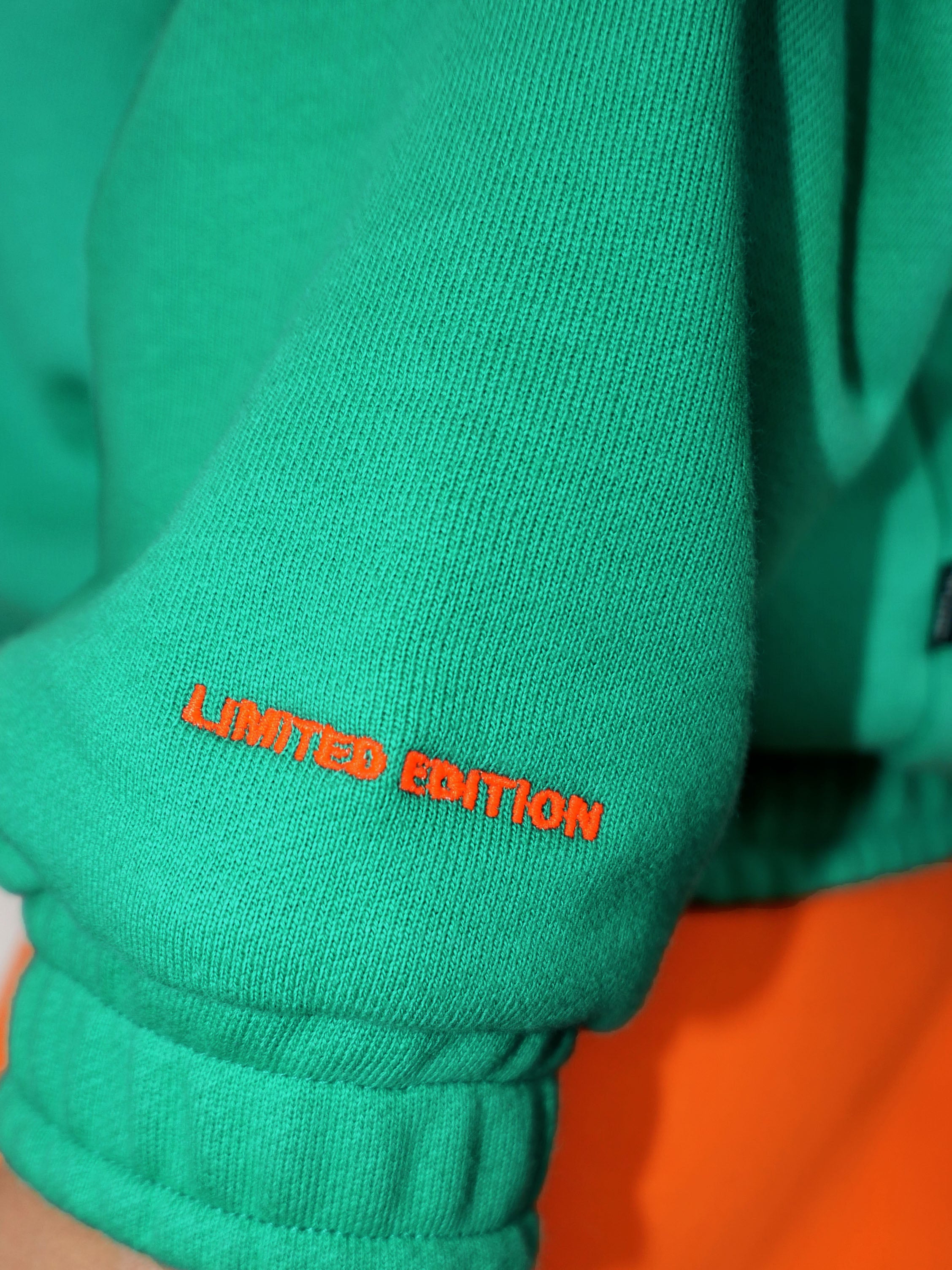Closeup of green sweatshirt with 'LIMITED EDITION' text in neon orange on sleeve