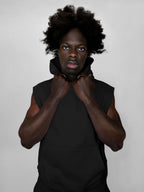 Person wearing a black sleeveless hoodie against a plain background