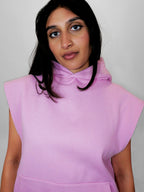 Person wearing a blush sleeveless hoodie against a plain background